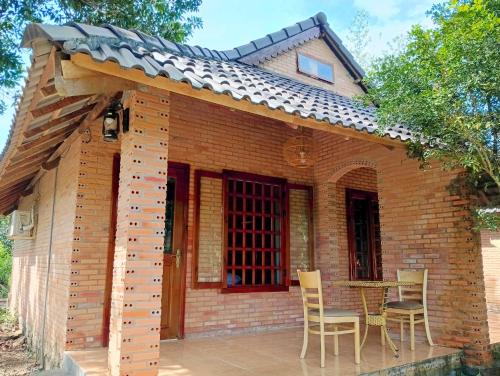 a small brick house with chairs and a table at Nam Cat Tien Retreat in Tân Phú