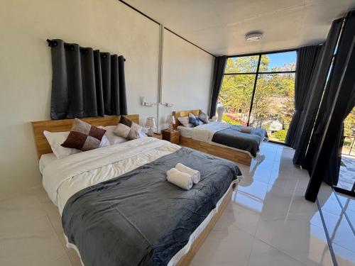 two beds in a room with black curtains at อินทนนท์ บ้านพักเล่าจู Inthanon Laoju House in Ban Na Yang