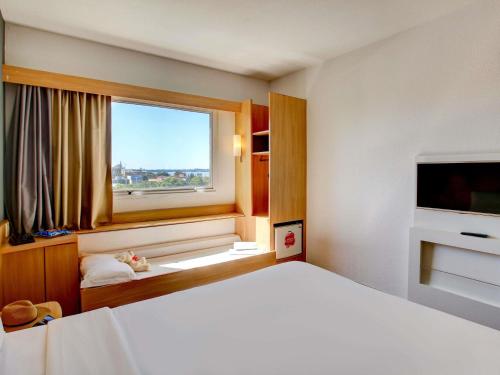 a bedroom with a large bed and a window at ibis Vitoria Praia do Canto in Vitória