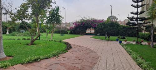 einen Ziegelweg in einem Park mit Bäumen und Sträuchern in der Unterkunft iris appart vue dégagée, bon emplacement in Salé