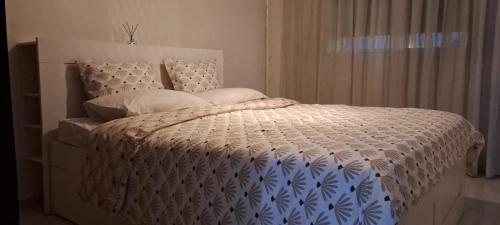 ein Bett mit einer weißen Bettdecke und Kissen darauf in der Unterkunft iris appart vue dégagée, bon emplacement in Salé