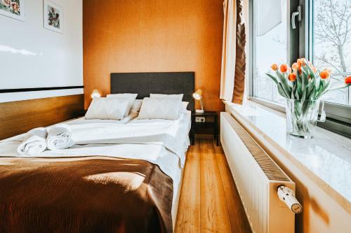 a bedroom with a bed and a vase of tulips at VisitZakopane - Cristal Apartment in Zakopane