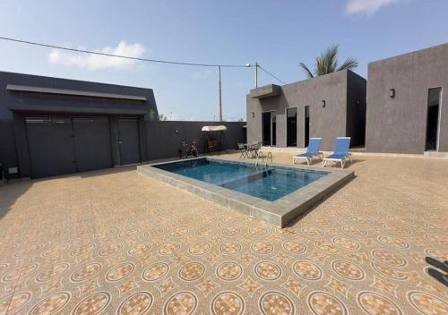 ein Swimmingpool mit zwei blauen Stühlen und einem Gebäude in der Unterkunft AKl RESIDENCE in Assinie
