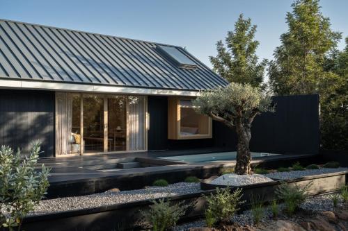 a black house with a tree in the front yard at Kuro Pool Villa Khaoyai in Ban Wang Sai