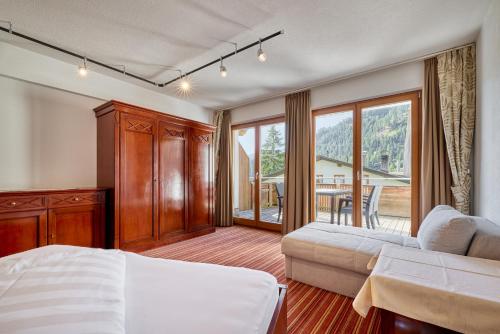 Un dormitorio con una cama y un sofá y un balcón. en Hotel Garni Philipp, en Serfaus