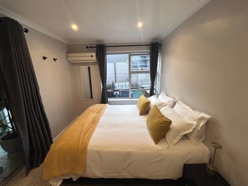 a bedroom with a bed with yellow pillows and a window at AquaPalms Hideaway - Family Friendly Pool - Hot Tub - Indoor Braai in Cape Town