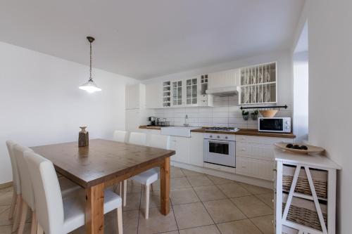 a kitchen with a wooden table and white cabinets at Vila Sistiana in Kostanjevica na Krasu