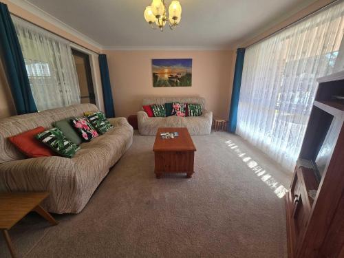 Una sala de estar con dos sofás y una mesa de café. en Seascape Macleay Street - walk to beach, en Narrawallee