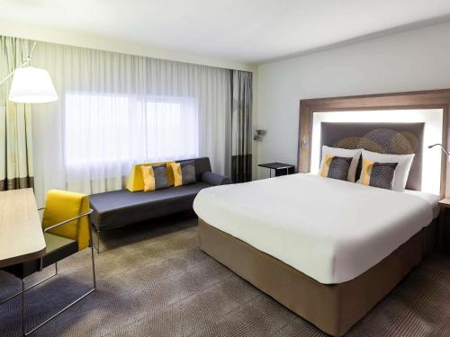 a hotel room with a large bed and a couch at Novotel The Hague World Forum in The Hague