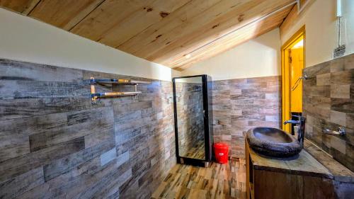 a bathroom with a large mirror and a wooden wall at Monkstel Cottages Shangarh in Shangarh