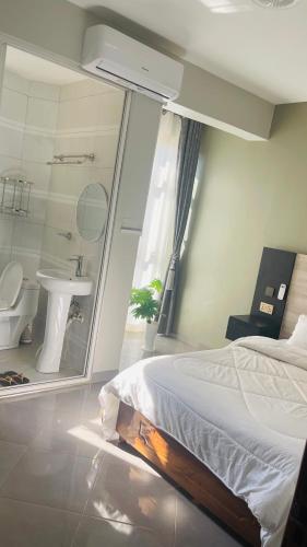 a bedroom with a bed and a bathroom with a sink at Opal Heights Hotel Nansana in Kyebando