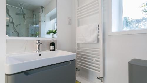 a white bathroom with a sink and a mirror at Rutherglen in Beaumaris
