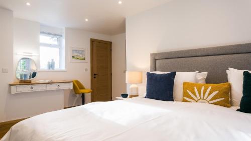 a bedroom with a white bed with blue and yellow pillows at Rutherglen in Beaumaris