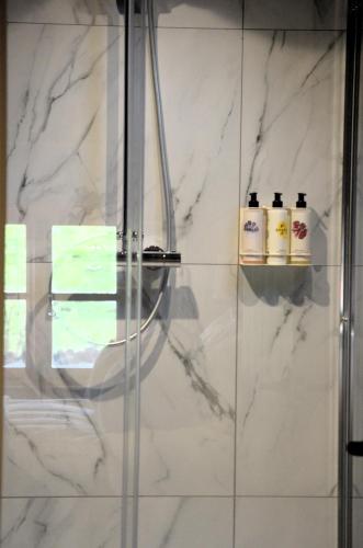 a bathroom with white marble walls and a shower at The Hollow Bottom in Guiting Power