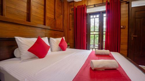 ein Schlafzimmer mit einem großen Bett mit roten und weißen Kissen in der Unterkunft Shady mango villa in Sigiriya