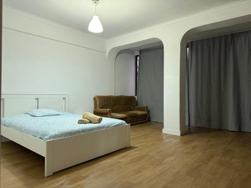a white bedroom with a bed and a chair at Bliss in Lisbon Humberto Delgado Airport