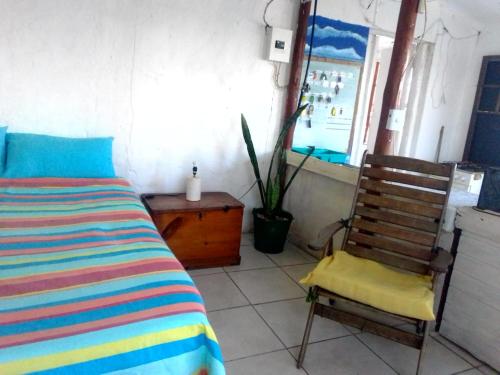 1 dormitorio con cama y silla de madera en Eagles Nest hostel plus self catering private units, en Coffee Bay