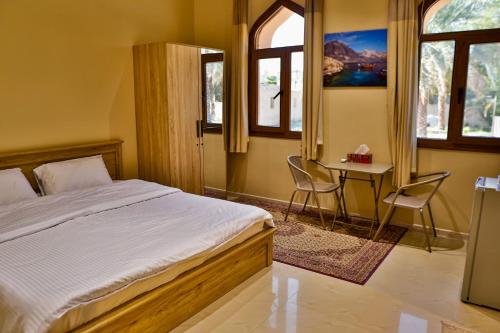 ein Schlafzimmer mit einem Bett und einem Tisch und Stühlen in der Unterkunft The Garden Inn نزل الحدیقة in Nizwa