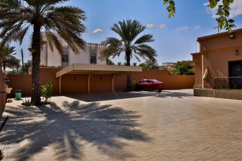 ein Auto, das vor einem Haus mit Palmen parkt in der Unterkunft The Garden Inn نزل الحدیقة in Nizwa