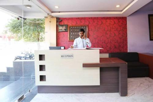 Ein Mann, der am Empfang telefoniert. in der Unterkunft Palette Hotels and Resorts Siva Vishnu Temple Formerly RC Resort in Perunkalattu