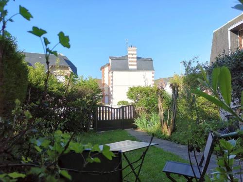 a garden with a wooden fence and a table at L'Acacia, F2 terrasse et jardin,plage à 400mètres in Houlgate