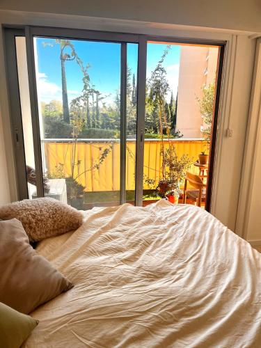 ein Bett in einem Zimmer mit einem großen Fenster in der Unterkunft Green cocoon in Mandelieu-la-Napoule