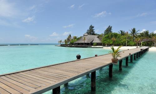 a dock in the water next to a tropical island at Komandoo Island Resort & Spa in Komandoo