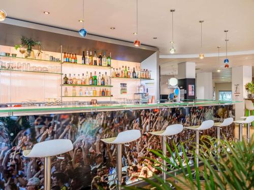 a bar with white stools in a restaurant at ibis Styles Strasbourg Stade de la Meinau in Strasbourg