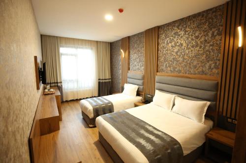 Una habitación de hotel con dos camas y una ventana. en Büpa delüxe hotel, en Kayseri