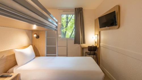 ein Schlafzimmer mit einem weißen Bett und einem Fernseher in der Unterkunft Premiere Classe Marne La Vallee - Saint Thibault Des Vignes in Saint-Thibault-des-Vignes