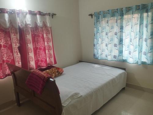Un dormitorio pequeño con una cama y dos ventanas. en 2 Bedroom apartment in Iskcon Mayapur, en mayapur