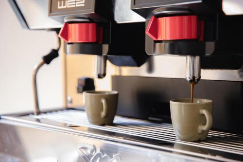 due tazze di caffè vengono fatte in una macchina da caffè di Duomo Home Bed&Breakfast a Agrigento