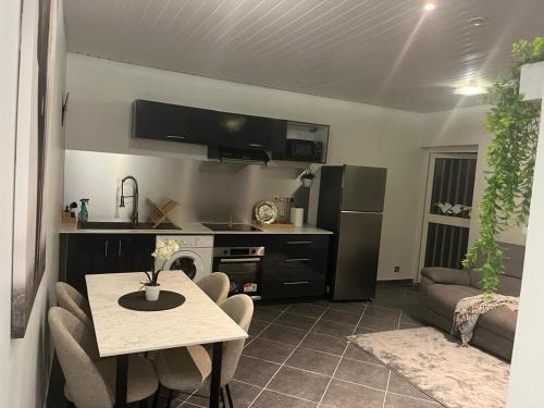 a kitchen and living room with a table and a refrigerator at T3 moderne avec piscine proche de Family Plaza in Matoury