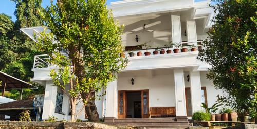 ein weißes Haus mit Bäumen davor in der Unterkunft Retreat Rivera where Serenity Meets the River in Green Island