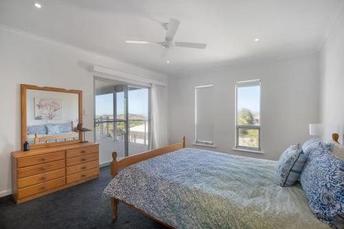 a bedroom with a bed and a dresser and windows at The Summer Residence Middleton in Middleton