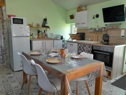 a kitchen with a wooden table with chairs and a kitchen with a refrigerator at La bergerie in Coussay