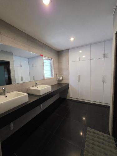 5 Bedroom Villa With Private Pool By Perkasa في كوالالمبور: حمام به مغسلتين ومرآة كبيرة