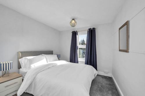 a white bedroom with a bed and a window at 17 OutRisbygate St - 3 bedroom house that sleeps 6 with one private parking space in Bury Saint Edmunds