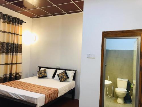 a small bedroom with a bed and a toilet at Shereen Sigiri Homertay in Dambulla