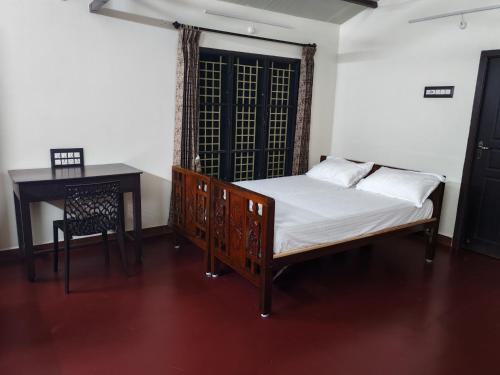 a bedroom with a bed and a desk and a table at The Sparrow House 1BHK First Floor in Kumbakonam