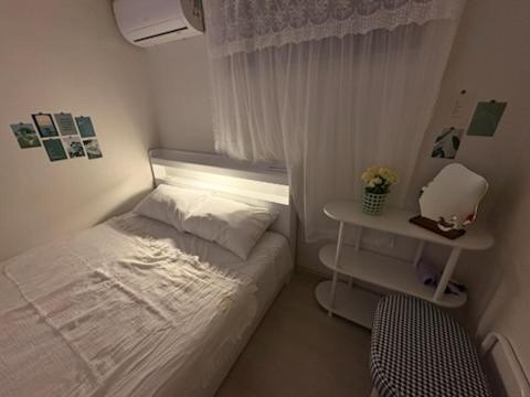 Dormitorio blanco pequeño con cama y mesa en stay110, en Seúl