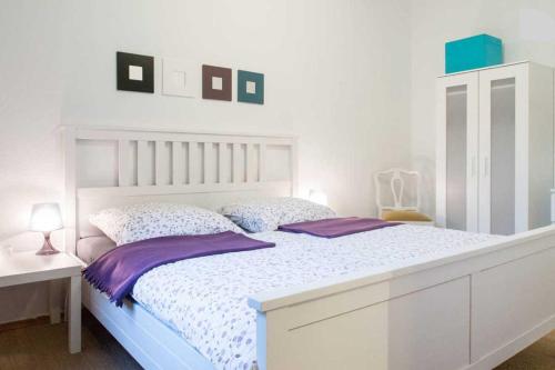 ein weißes Schlafzimmer mit einem weißen Bett und lila Kissen in der Unterkunft Altstadt Ferienwohnung Wagner in Limburg an der Lahn