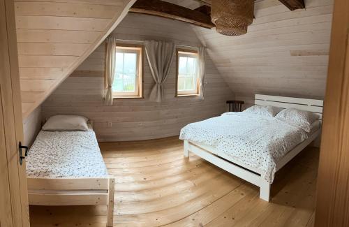 a bedroom with two beds and two windows at Roubenka in Terchová