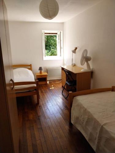 a bedroom with a bed and a desk and a window at La maison du fermier in Chauvigny