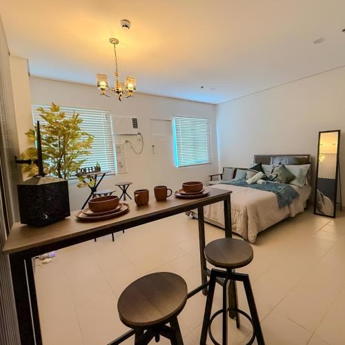 a bedroom with a bed and a table and two stools at Unwind with Peace at Cheer Residences SM Marilao-Philippine Arena in Marilao