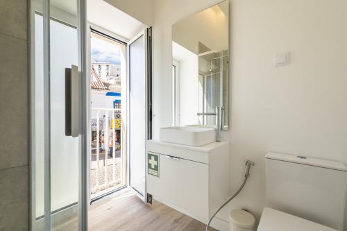 a white bathroom with a sink and a window at Downtown 1 Bedroom Apartment E - 150m from the Beach in Albufeira