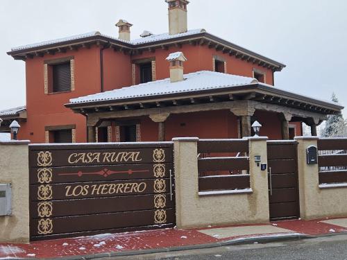 a building with a sign in front of a fence at Casa Rural Los Hebrero in Torrecaballeros