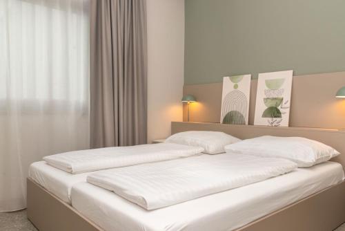 zwei Betten in einem Zimmer mit weißen Wänden in der Unterkunft HANS-Y Apartments inklusive Outdoorpool & Bar in Wien