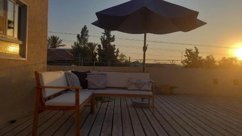 a bench sitting on a deck with an umbrella at על הגג במדבר in Mitzpe Ramon