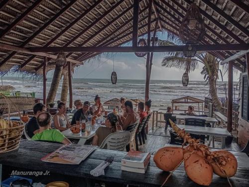 a group of people sitting at a restaurant on the beach at Ocean Breeze Villa in Matara